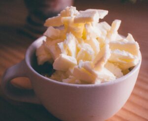 A pile of butter curls stacked in a white ceramic mug on a wooden table.